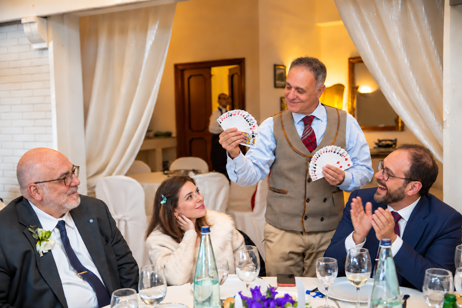 Gli ospiti applaudono divertiti durante un effetto di magia al ricevimento